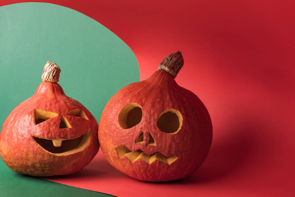 Spooky Halloween pompoenen op rode en groene achtergrond - Foto, afbeelding