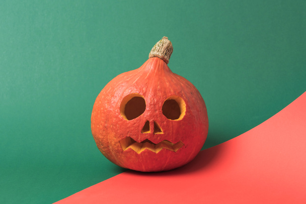 Gruseliger Halloween-Kürbis auf rotem und grünem Hintergrund - Foto, Bild