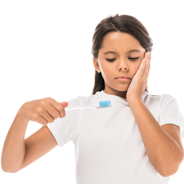 αναστατωμένος παιδί κοιτάζοντας οδοντόβουρτσα απομονωμένη σε λευκό  - Φωτογραφία, εικόνα
