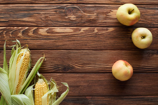 vista superior de manzanas frescas maduras y maíz dulce en la superficie de madera marrón con espacio para copiar
 - Foto, Imagen