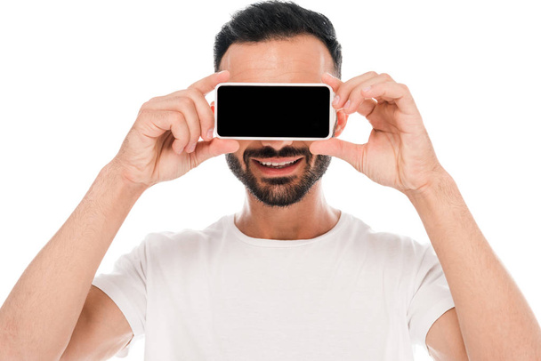homme barbu couvrant les yeux tout en tenant smartphone avec écran blanc isolé sur blanc
  - Photo, image
