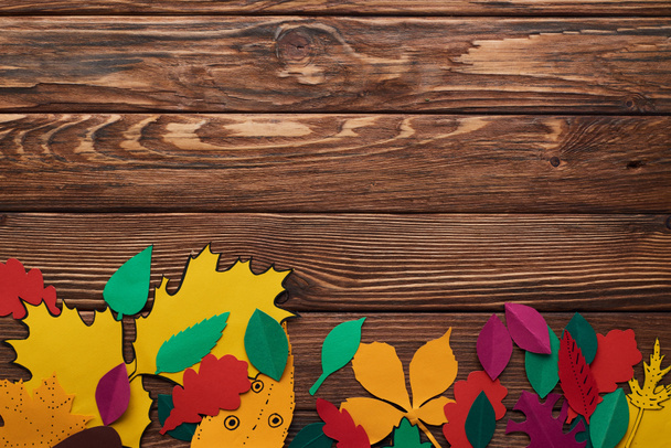 Κορυφαία όψη του πολύχρωμου χαρτιού φύλλα σε καφέ ξύλινη επιφάνεια - Φωτογραφία, εικόνα
