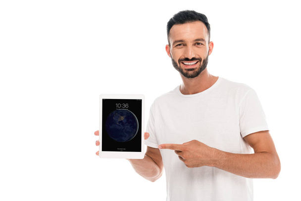 KYIV, UKRAINE - SEPTEMBER 3, 2019: Happy bearded man pointing with finger at ipad  isolated on white - 写真・画像
