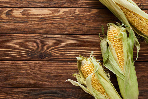 top view of fresh corn on wooden surface - Fotó, kép