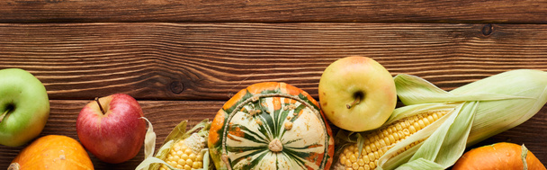 panoramic shot of fresh apples, pumpkins and sweet corn on wooden surface  - Photo, Image