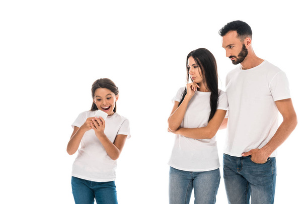 γονείς κοιτάζοντας χαρούμενος παιδί χρησιμοποιώντας smartphone απομονώνονται σε λευκό  - Φωτογραφία, εικόνα