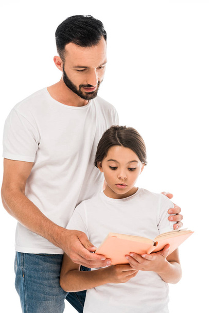 schöner Vater steht neben Tochter und liest Buch isoliert auf weißem Grund  - Foto, Bild
