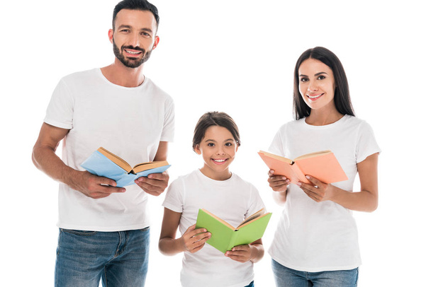 ευτυχισμένη οικογένεια κρατώντας βιβλία, ενώ χαμογελά απομονωμένη σε λευκό  - Φωτογραφία, εικόνα