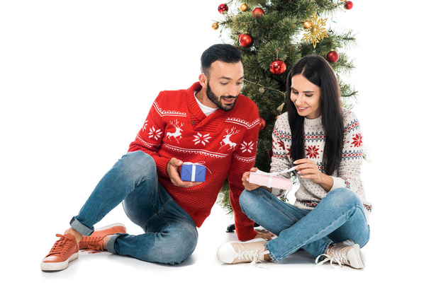homem feliz e mulher segurando presentes perto da árvore de Natal isolado no branco
 - Foto, Imagem