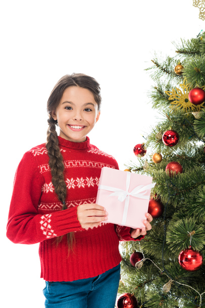 cheerful kid holding pink present near christmas tree isolated on white  - Zdjęcie, obraz