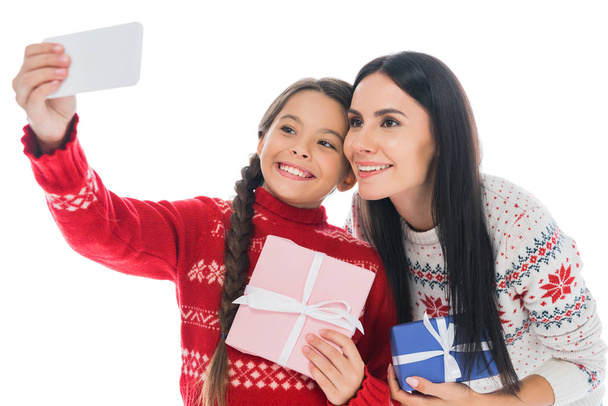 happy mother and daughter in sweaters taking selfie with present isolated on white  - Photo, Image