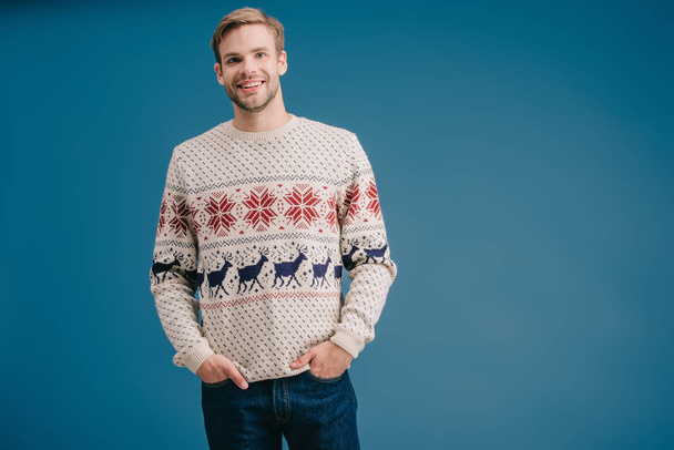 handsome smiling man posing in winter sweater isolated on blue - Foto, immagini
