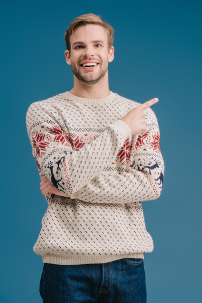 uomo sorridente in maglione invernale che punta a qualcosa di isolato sul blu
 - Foto, immagini
