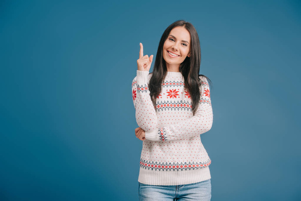 cheerful woman in winter sweater pointing at something isolated on blue - Foto, immagini