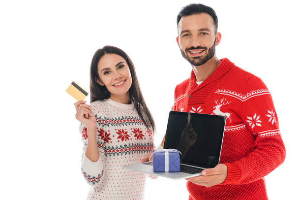 happy man holding laptop with present near cheerful woman with credit card isolated on white  - 写真・画像