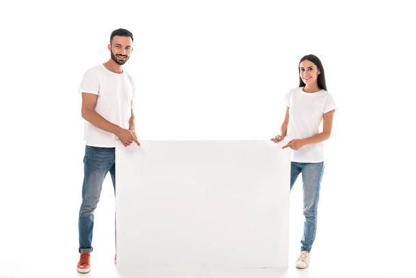 boldog szakállas férfi és nő áll közel üres plakát elszigetelt fehér  - Fotó, kép