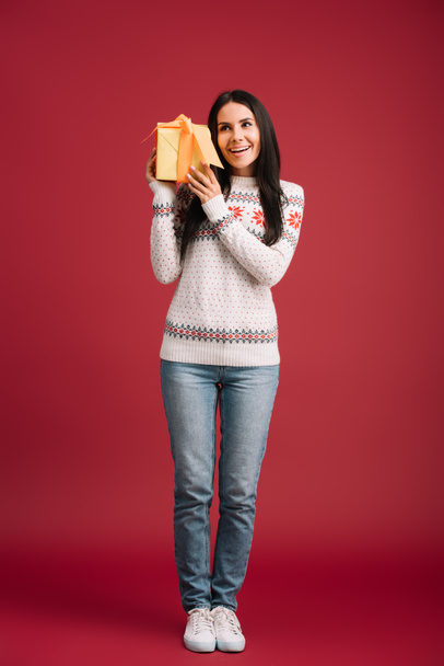 beautiful happy woman holding christmas present isolated on red - Photo, Image