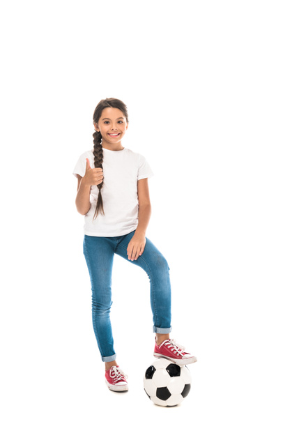 happy kid standing with football and showing thumb up isolated on white  - Fotó, kép