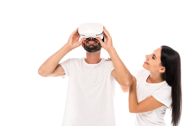 glückliche Frau sieht bärtigen Mann mit Virtual-Reality-Headset isoliert auf weiß  - Foto, Bild
