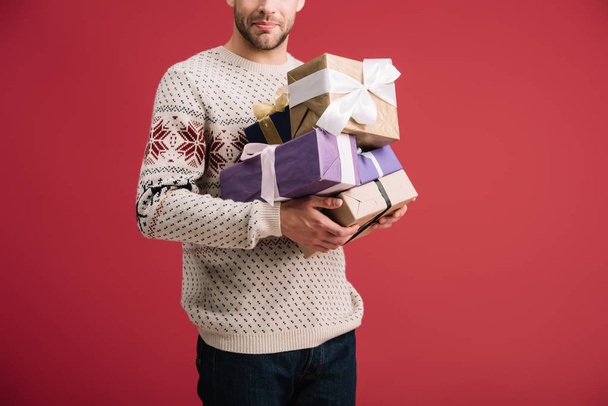 abgeschnittene Ansicht eines Mannes mit Weihnachtsgeschenkboxen isoliert auf rot - Foto, Bild