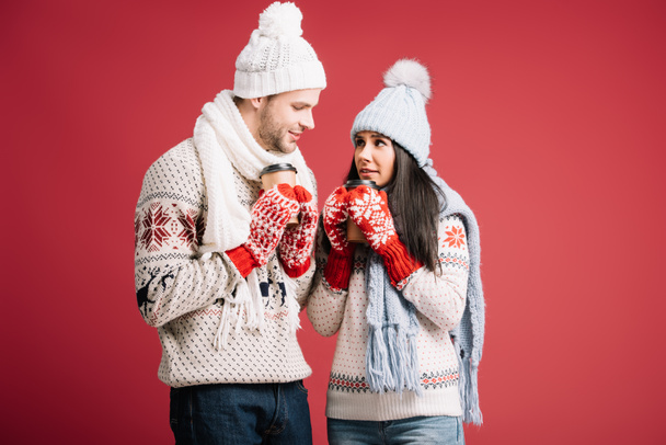 happy couple in sweaters, hats, scarves and mittens holding coffee to go isolated on blue - Photo, Image