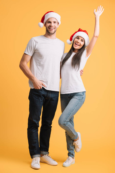 coppia eccitata in cappelli di Babbo Natale divertirsi sul giallo
 - Foto, immagini