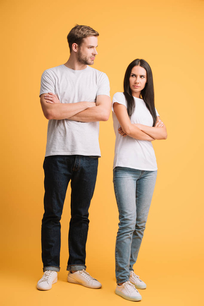 offended couple in bad mood standing with crossed arms on yellow - Photo, Image