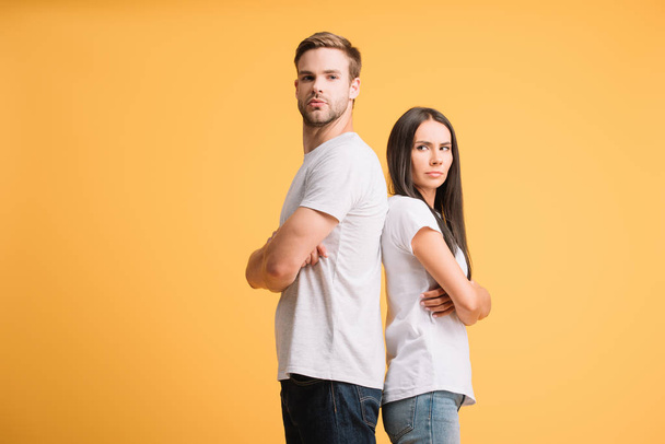offended couple standing with crossed arms, isolated on yellow - Foto, Bild