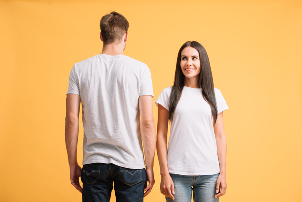 beautiful smiling couple posing in white t-shirts, isolated on yellow - Zdjęcie, obraz