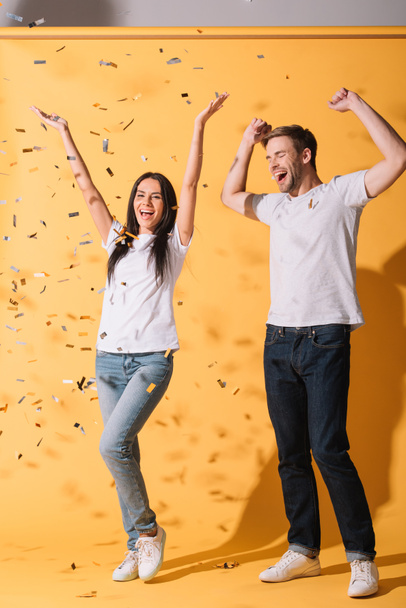 happy couple have fun on yellow with golden confetti - Foto, Imagen