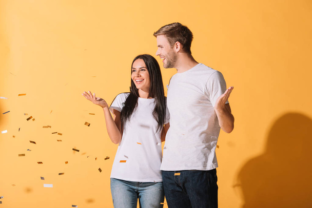 beautiful couple hugging on yellow with golden confetti - Foto, afbeelding