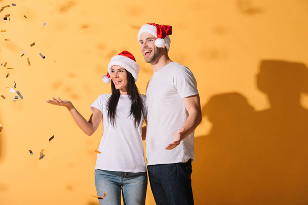 couple excité chapeaux santa étreignant sur jaune avec des confettis dorés
 - Photo, image