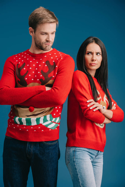 sértett pár karácsonyi pulóverek állt keresztbe karokkal izolált kék - Fotó, kép