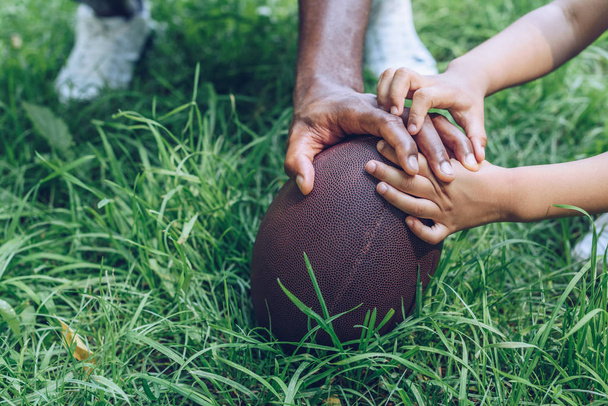 cropped view of african american father and son touching rugby ball - Photo, Image