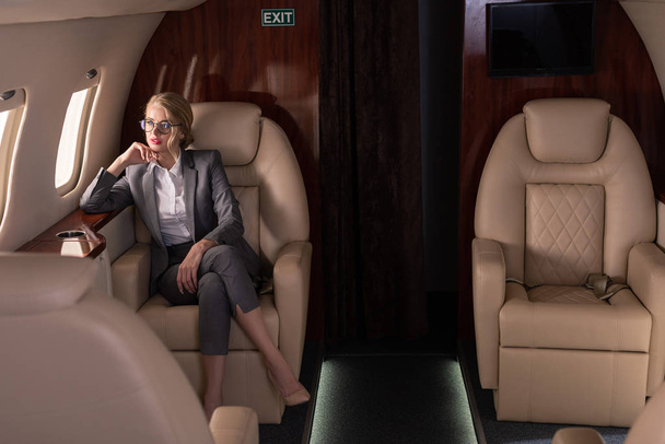 beautiful blonde businesswoman sitting in plane during business trip - Foto, Imagen