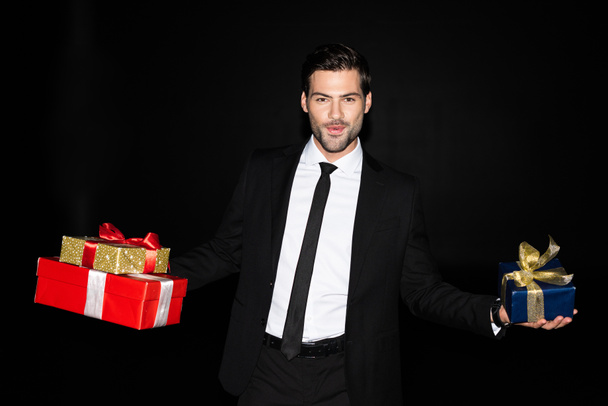 happy man holding gift boxes, isolated on black - Foto, imagen