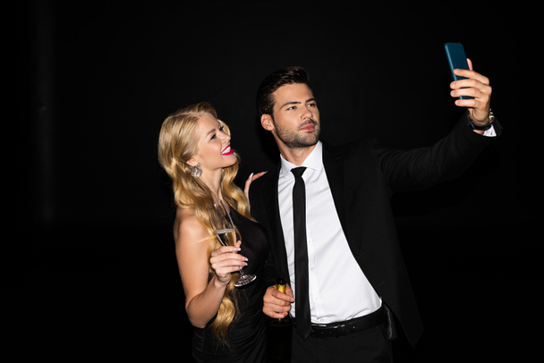 piękny para biorąc selfie na smartfon z okulary na szampan odizolowany na czarny  - Zdjęcie, obraz