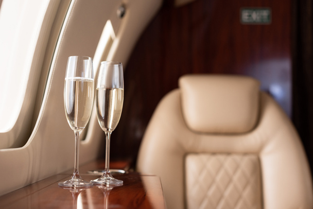 selective focus of interior of plane with champagne glasses for trip - Foto, imagen