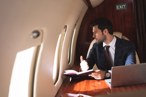 jeune homme d'affaires travaillant avec ordinateur portable et ordinateur portable en avion pendant le voyage d'affaires
  - Photo, image