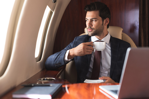 uomo d'affari in giacca e cravatta bere caffè in aereo durante il viaggio d'affari
 - Foto, immagini