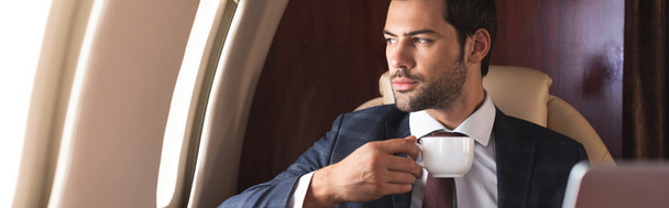 uomo d'affari fiducioso in tuta bere caffè in aereo durante il viaggio d'affari
 - Foto, immagini