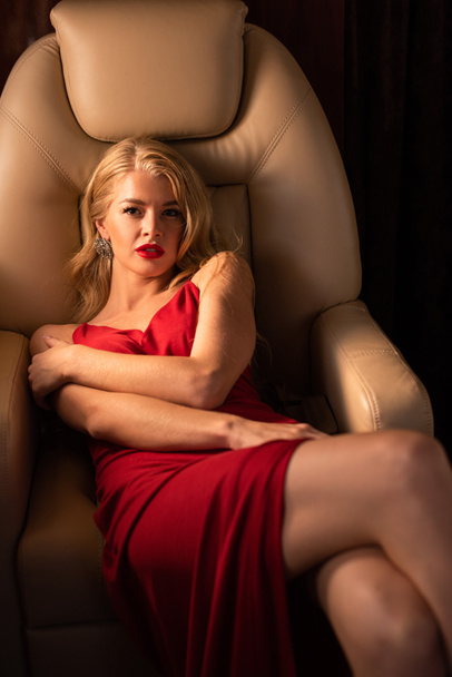 sexy young woman in red dress sitting in plane - Zdjęcie, obraz