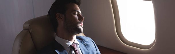 handsome businessman sleeping in plane during business trip - 写真・画像