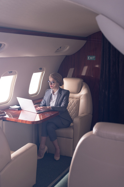 professional businesswoman working on laptop in plane during business trip  - 写真・画像