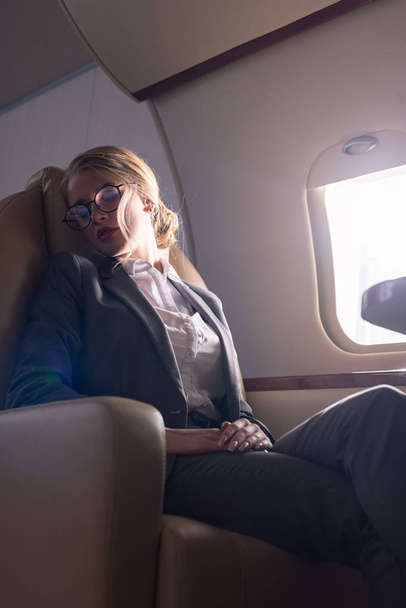attractive businesswoman sleeping in plane during business trip - 写真・画像