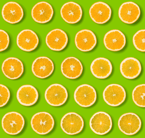 Seamless pattern of orange fruit slices on green background. Fla - Valokuva, kuva