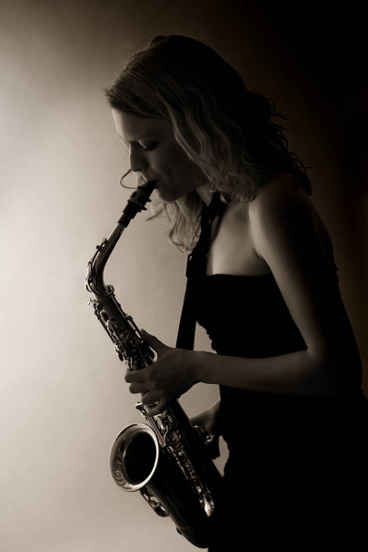 Крупним планом жінка грає на саксофоні, сепія тонована
. - Фото, зображення