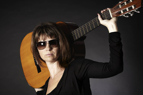 Woman posing with guitar on shoulders. - Photo, image
