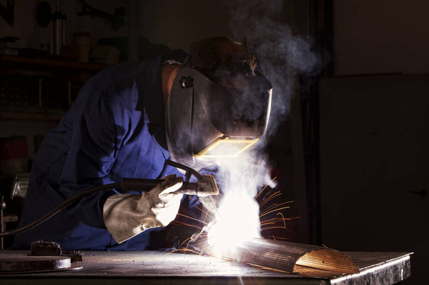 Worker welding in workshop. - Zdjęcie, obraz
