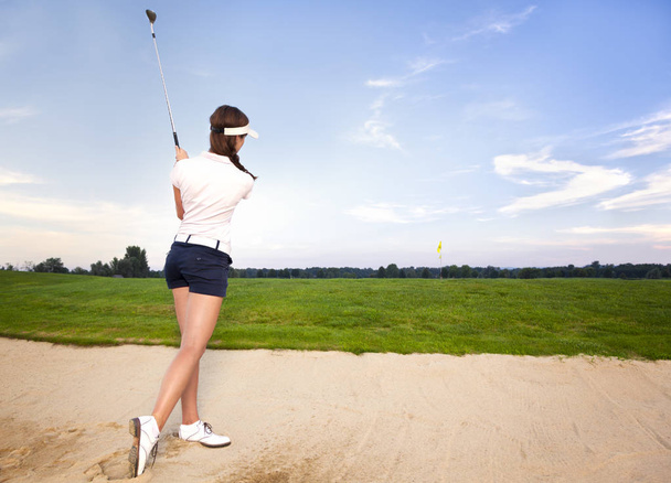 Girl golf player in bunker chipping ball. - Fotografie, Obrázek